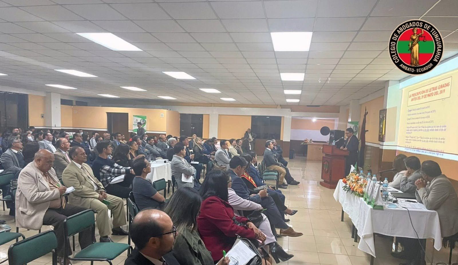 Auditorio lleno de abogados escuchando a un expositor en el podio, con una presentación proyectada sobre letras de cambio