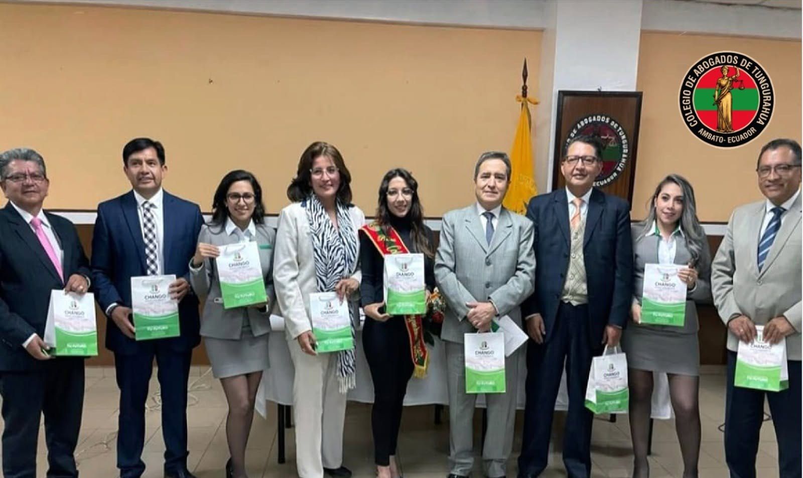 Grupo de abogados y abogadas posando con carpetas y certificados en el salón del Colegio